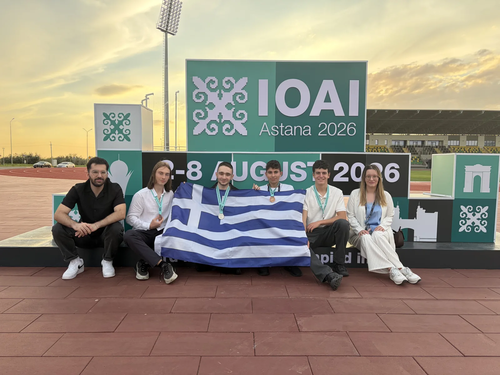 Group photo with the Greek flag at IOAI 2026 in Astana